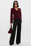 Woman models classic Black Kalinda Pant with wide-leg design, high waistband, and pressed crease, paired effortlessly with a burgundy cardigan and accessories for a high-end, fun look.