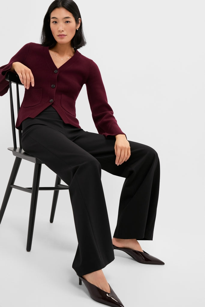 Woman models classic Black Kalinda Pant with a high-rise, wide-leg fit, exuding effortless style. Perfectly paired with a chic cardigan and glossy slip-ons.