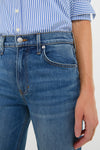 Close-up of a person wearing Rebel Blue Harley High Rise Arc Leg jeans with a striped shirt, showcasing a classic, effortless high-end style with a modern silhouette.