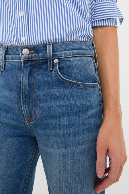 Close-up of a person wearing Rebel Blue Harley High Rise Arc Leg jeans with a striped shirt, showcasing a classic, effortless high-end style with a modern silhouette.