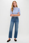 Woman wearing classic Rebel Blue Harley High Rise Arc Leg jeans with a subtle barrel leg and high-end stretch denim. Effortless, fun style with rolled blouse sleeves and black flats.