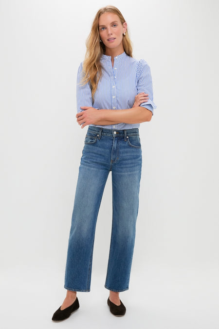Woman wearing classic Rebel Blue Harley High Rise Arc Leg jeans with a subtle barrel leg and high-end stretch denim. Effortless, fun style with rolled blouse sleeves and black flats.