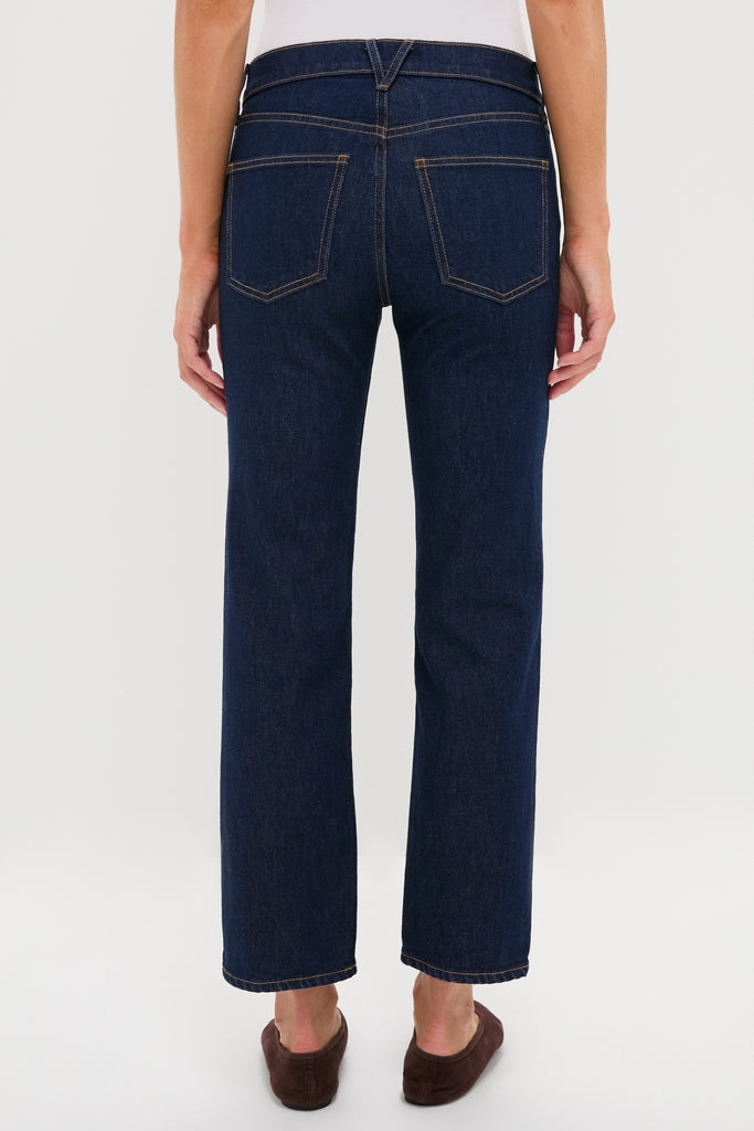 Person in classic Indigo Rinse Leah Mid Rise Straight Leg jeans, showcasing contrasting stitched back pockets and waistband, paired with an effortless white top and fun brown slip-on shoes.