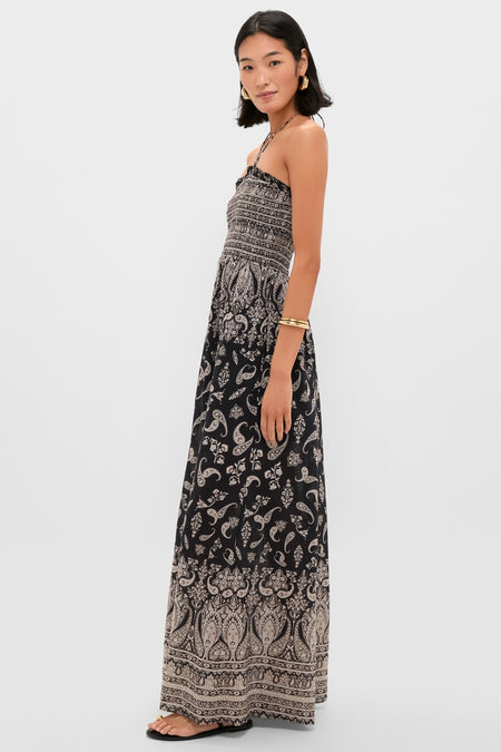 Woman in profile wearing the classic Black Multi Ayanna Dress, featuring an effortless paisley print and smocked bodice, accessorized with gold hoops and bangles, exuding fun and high-end style.