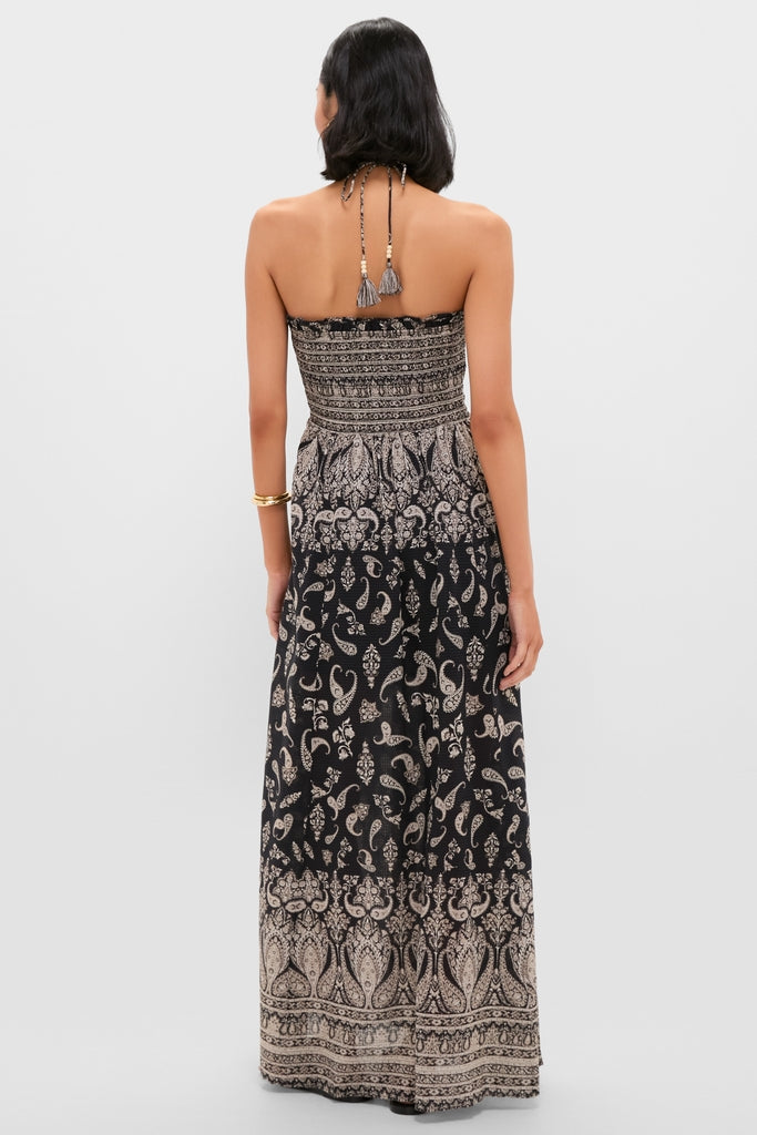 Woman in a classic, high-end Black Multi Ayanna Dress with a paisley print. The strapless dress is effortless and fun, featuring a smocked bodice and tasseled neck ties.