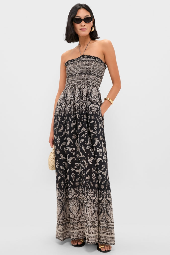 Woman models the Black Multi Ayanna Dress, a classic boho maxi with a smocked bodice and paisley skirt, accessorized with sunglasses, straw handbag, and gold jewelry for an effortless, high-end look.