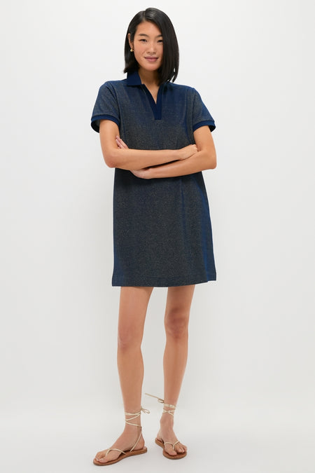 Woman modeling the Navy Gold Lurex Pique Hutton Dress, a classic, effortless mid-thigh polo-style dress in shimmering navy, paired with fun, high-end tan strappy sandals.