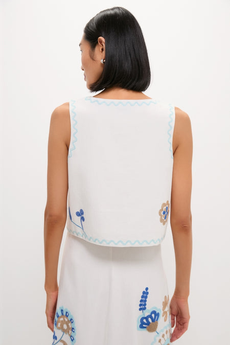 Woman wearing the classic Folk Flower Embroidered Luna Top, showcasing effortless style with fun floral appliqués and high-end detailing against a minimalist backdrop.