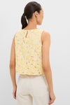 Woman wearing the Pale Yellow Flower Vera Top, showcasing its sleeveless, boxy-cut design with classic floral lace, paired with high-waisted, patch-pocket cream pants for an effortless, high-end look.