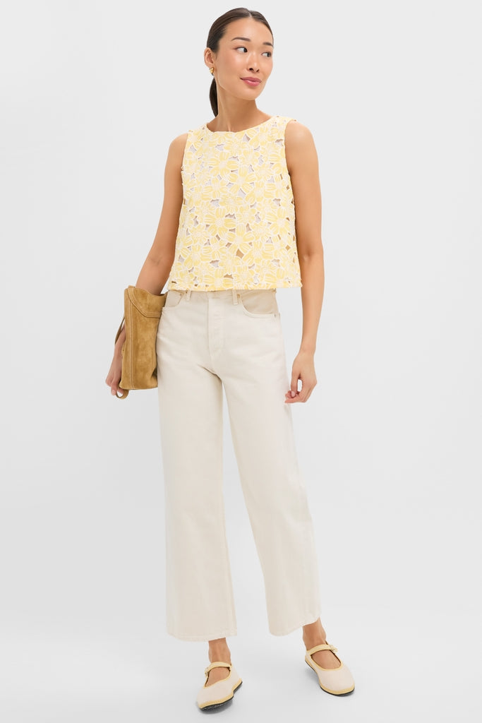 Young woman wearing the classic, effortless Pale Yellow Flower Vera Top with floral cutouts, paired with high-end cream wide-leg jeans and fun Mary-Jane flats.