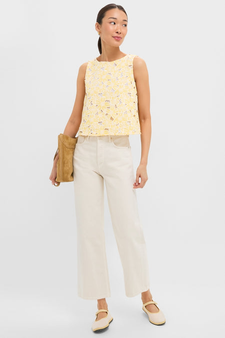 Young woman wearing the classic, effortless Pale Yellow Flower Vera Top with floral cutouts, paired with high-end cream wide-leg jeans and fun Mary-Jane flats.