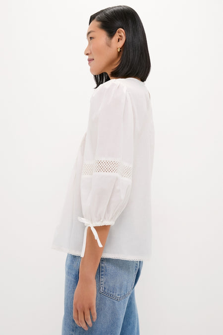 White Bella Blouse with relaxed fit, eyelet detailing, and bow-tied three-quarter sleeves. Paired with classic blue jeans for an effortless, high-end everyday look.
