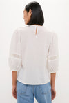Back view of White Bella Blouse with classic, effortless design; features relaxed fit, eyelet detailing, and keyhole button closure. Paired with high-waisted jeans for a fun, high-end look.