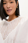 Young woman wears the classic White Bella Blouse with effortless eyelet detailing, relaxed fit, and blouson sleeves, embodying a fun, high-end style.