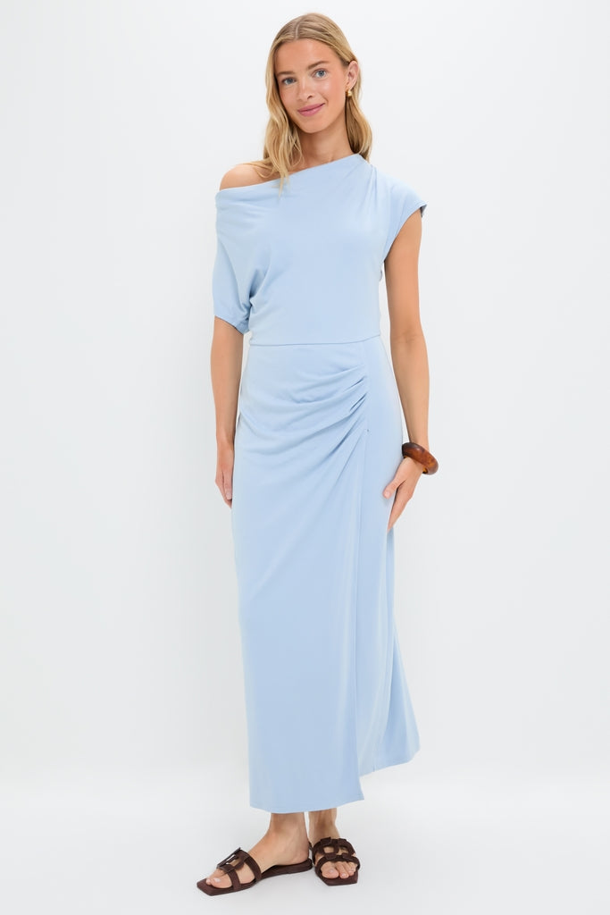 Young woman models the Blue Fog Faux Wrap Senna Dress, showcasing its classic, effortless drape and fun, high-end style, paired with brown sandals and a wooden bangle.