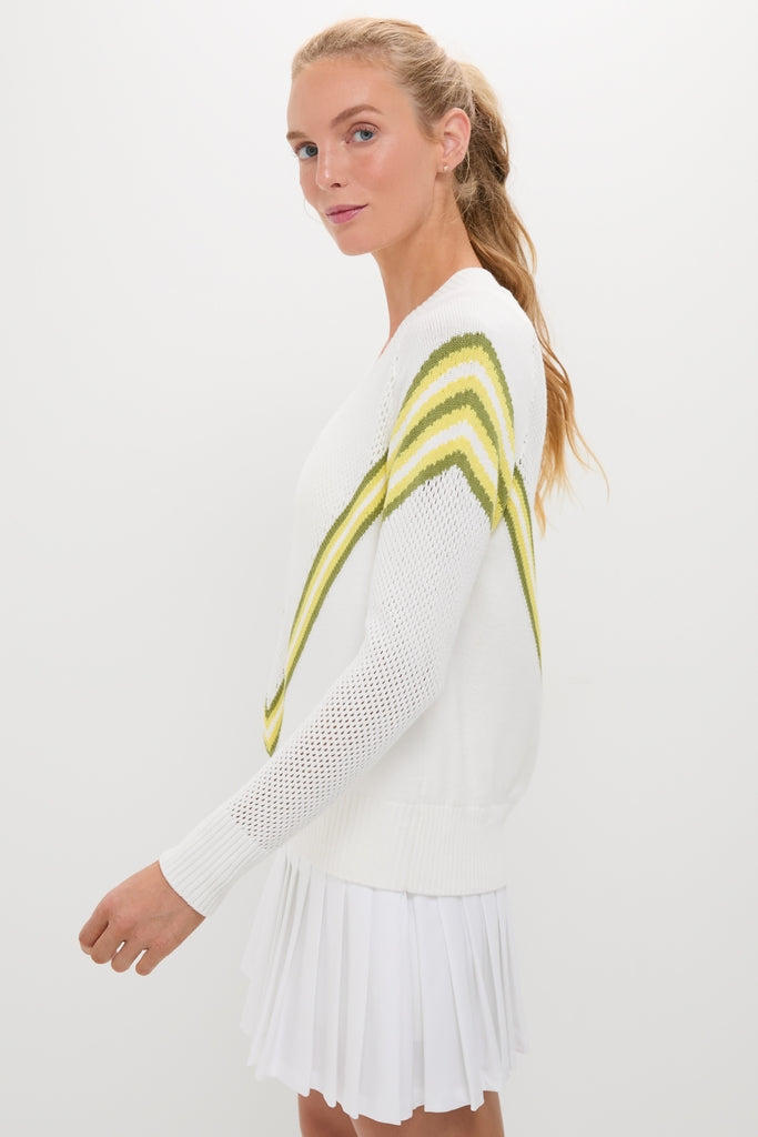 Woman in profile wearing the Yellow Emaline V-Neck Pullover, a classic and effortless sweater with green and yellow stripes, paired with a pleated mini skirt.