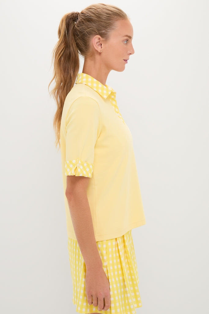 Woman in Lemon Yellow Prynn Polo with gingham collar and cuffs, paired with a matching pleated skirt, embodying classic, effortless, and fun high-end style.