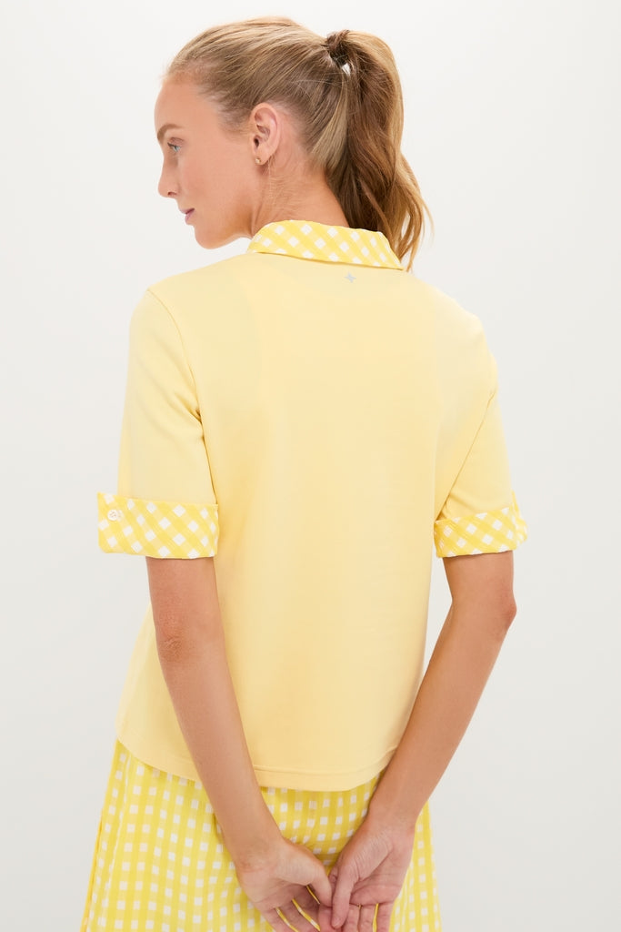 Woman in a Lemon Yellow Prynn Polo, showcasing a classic and effortless style with its gingham accents, paired with a matching gingham skirt for a fun, high-end look.