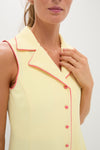 Woman wearing sleeveless Lemon Yellow Georgia Golf Dress with bright pink piping and buttons, exuding a classic, effortless, and fun high-end style.