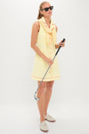 Woman in Lemon Yellow Georgia Golf Dress, effortlessly styled with a matching sweater and loafers, exuding classic, high-end fashion while holding a golf club.