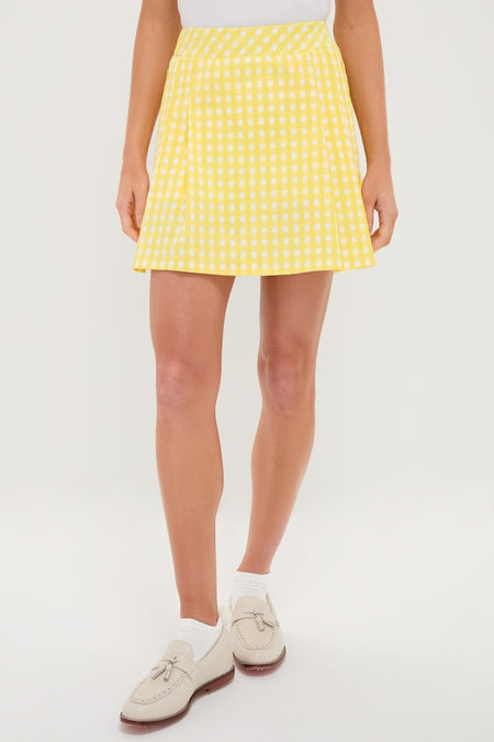 Model wears the classic Yellow Gingham Performance Jersey Park Golf Skirt, featuring an effortless A-line silhouette, elastic waistband, and placed pleating, paired with white socks and cream loafers.