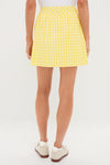 Person's back wearing the classic Yellow Gingham Performance Jersey Park Golf Skirt, showcasing effortless pleats and sporty charm, paired with fun, high-end slip-on shoes.