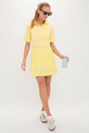 Woman wearing classic Yellow Gingham Performance Jersey Park Golf Skirt, showcasing an effortless, fun, high-end sporty look with pleated design and stylish accessories.