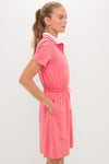 Woman in profile wearing the classic Coral Short Sleeve Performance Jersey Alcott Golf Dress, featuring an effortless drawstring waist, side pockets, and a high-end tipped collar.