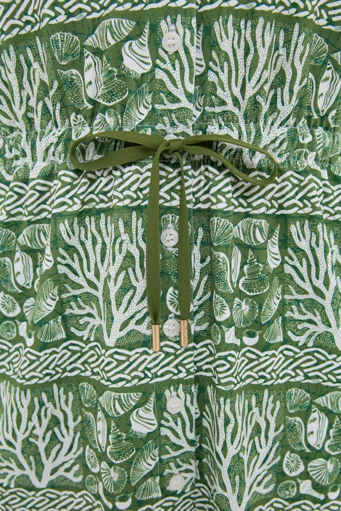 Calypso Reef Sleeveless Performance Jersey Alcott Golf Dress with a chic coral-and-shell print, button front, and drawstring waist, offering an effortless, high-end look for active days.