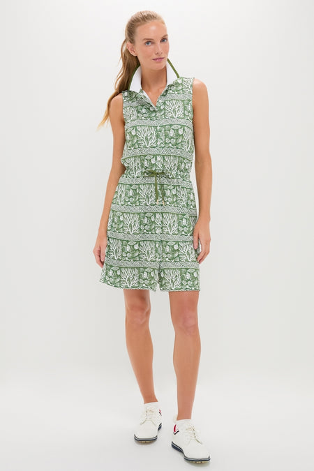 Woman models the classic Calypso Reef Sleeveless Performance Jersey Alcott Golf Dress, featuring an effortless sporty-casual look with fun botanical prints and a high-end, drawstring waist design.