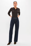 Woman models the Chocolate Fine Rib Knit Button Down Myers Polo, paired with high-waisted jeans and heeled ankle boots, embodying a classic, effortless, and high-end style.