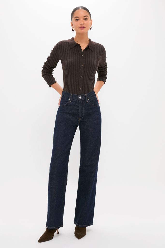 Woman models the Chocolate Fine Rib Knit Button Down Myers Polo, paired with high-waisted jeans and heeled ankle boots, embodying a classic, effortless, and high-end style.