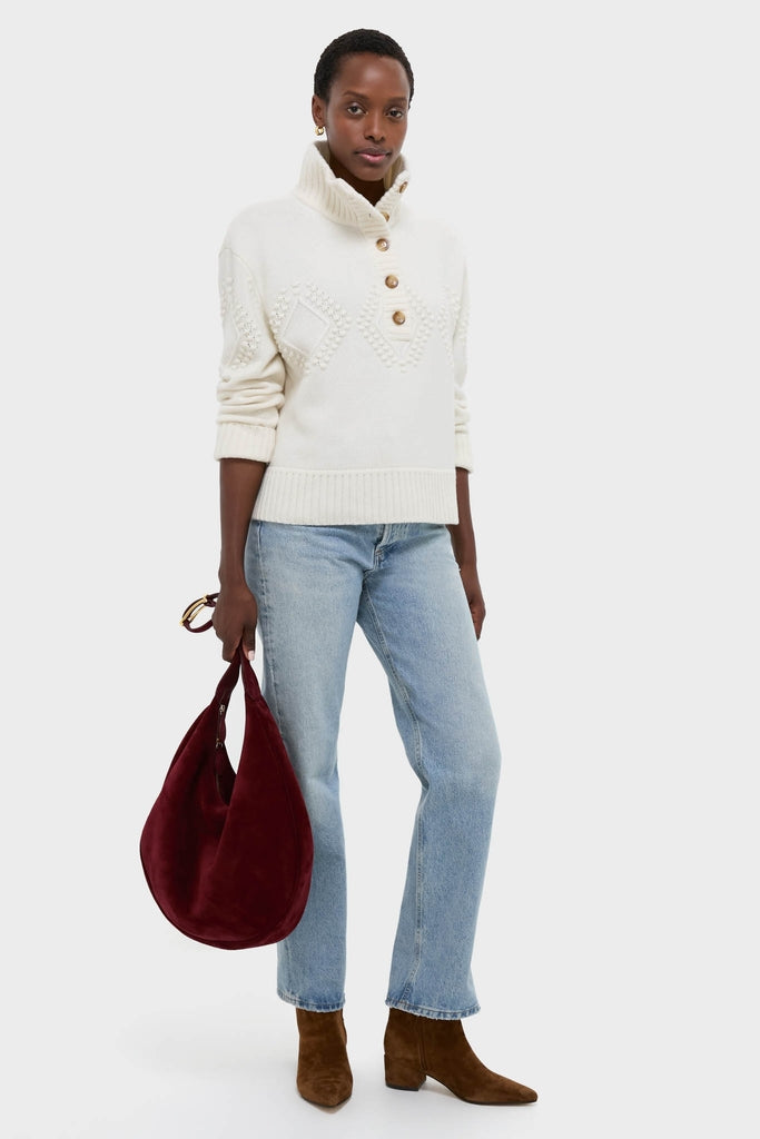 Woman wearing the Ivory Henry Button-Up Sweater, showcasing its classic textured pattern and high-end, effortless style, paired with jeans and boots for a fun, chic look.