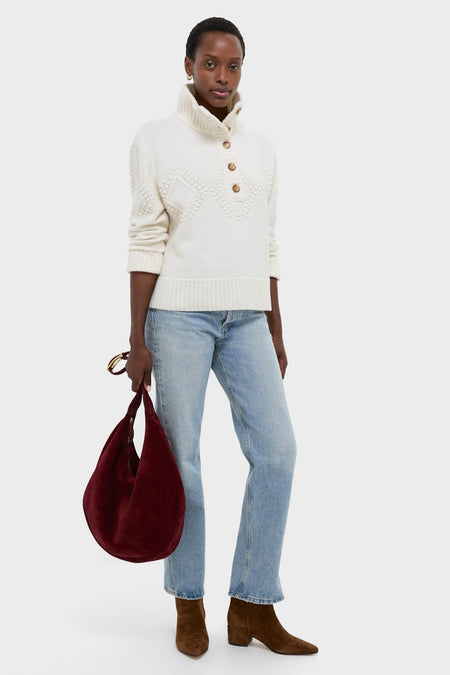 Woman wearing the Ivory Henry Button-Up Sweater, showcasing its classic textured pattern and high-end, effortless style, paired with jeans and boots for a fun, chic look.