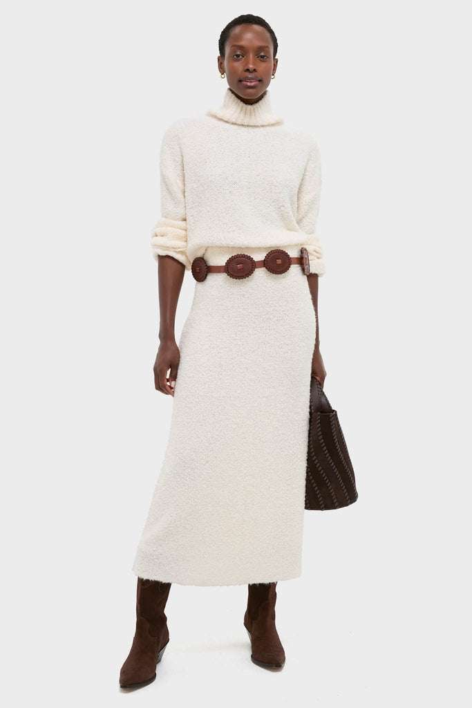 Model in classic Ivory Boucle Lillia Sweater Skirt with matching turtleneck, cinched by a dark belt. Effortless, high-end winter ensemble with fun, chic details.