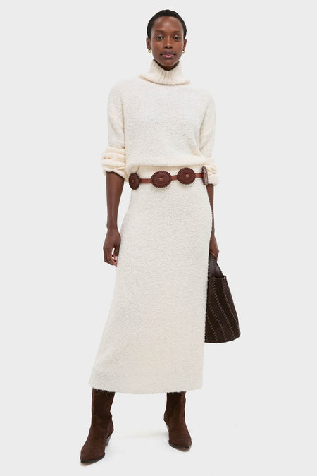 Model in classic Ivory Boucle Lillia Sweater Skirt with matching turtleneck, cinched by a dark belt. Effortless, high-end winter ensemble with fun, chic details.