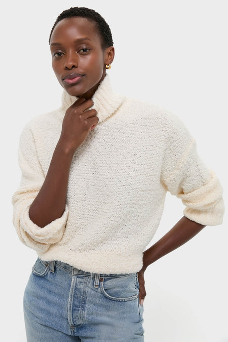 Woman in Ivory Boucle Whilden Sweater Top, showcasing a classic, effortless look with a chunky turtleneck and ribbed finishes, embodying fun and high-end style.