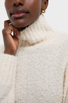 Person wearing the Ivory Boucle Whilden Sweater Top, a classic, high-end ribbed turtleneck, effortlessly chic with a relaxed fit, showcasing the boucle texture and fun, cozy elegance.