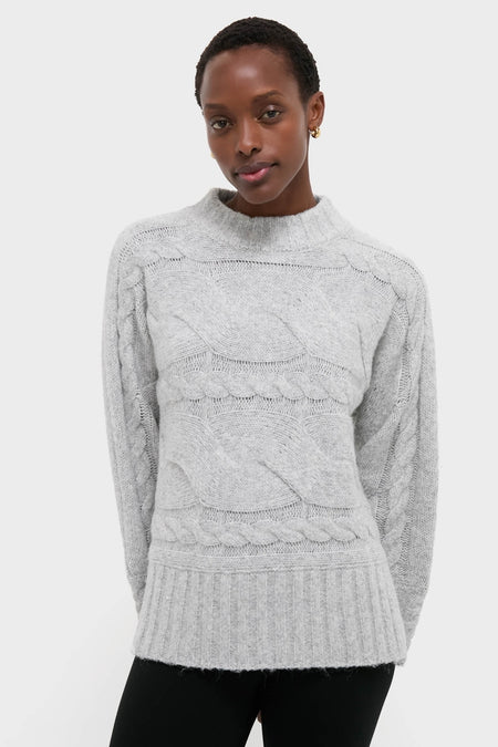Gray Cableknit Gladwyn Sweater on model, showcasing classic braided pattern, mock neck, and ribbed hem. An effortlessly chic, high-end piece for fun, confident style.