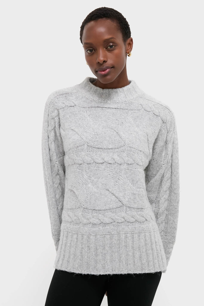 Gray Cableknit Gladwyn Sweater on model, showcasing classic braided pattern, mock neck, and ribbed hem. An effortlessly chic, high-end piece for fun, confident style.