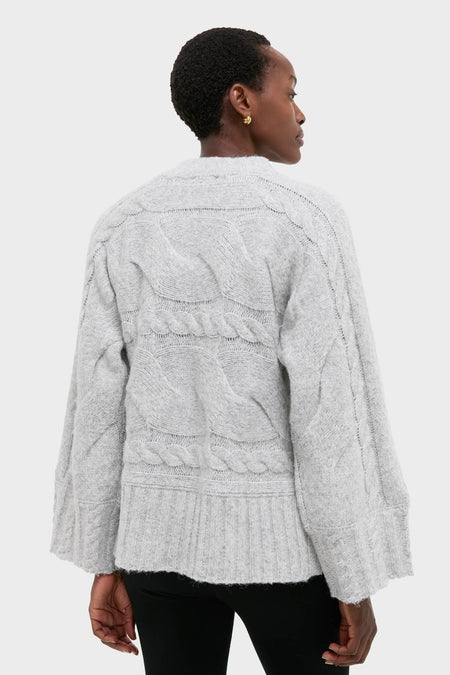 Person wearing Gray Cableknit Gladwyn Sweater with wide sleeves and ribbed hem, embodying a classic and effortlessly chic, high-end style against a plain backdrop.