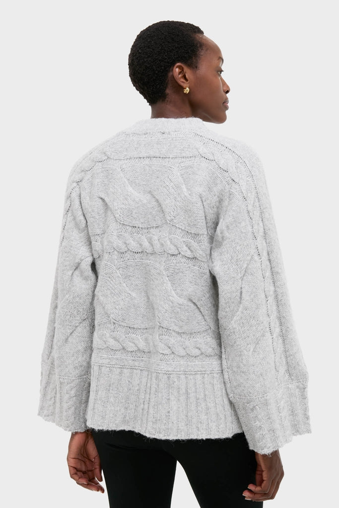 Person wearing Gray Cableknit Gladwyn Sweater with wide sleeves and ribbed hem, embodying a classic and effortlessly chic, high-end style against a plain backdrop.