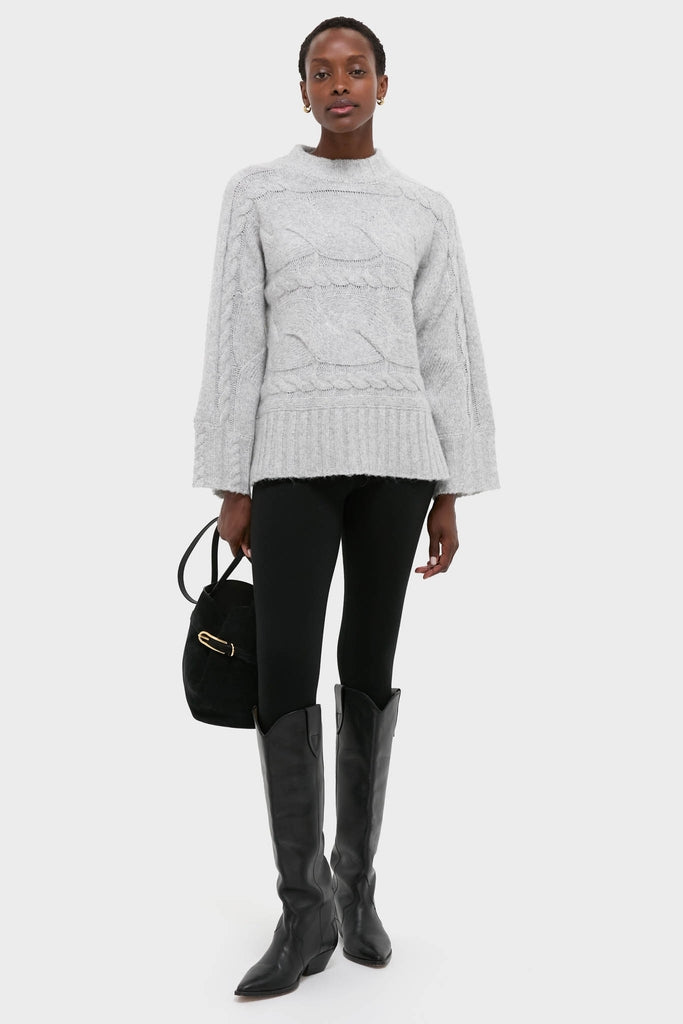 Gray Cableknit Gladwyn Sweater styled effortlessly with leggings and boots for a classic, high-end look, exuding fun and warmth with its chic cable-knit design.