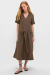 Young woman in the classic, effortless Tobacco Brown Crinkled Taffeta Check Long Dress with V-neckline, drop-waist, and midi length, paired with black sandals.