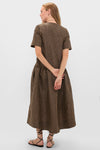 Woman in a classic, effortless Tobacco Brown Crinkled Taffeta Check Long Dress, featuring a V-neckline and drop waist, paired with black sandals.