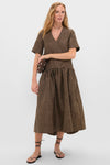 Model wearing Tobacco Brown Crinkled Taffeta Check Long Dress with V-neck and short sleeves, styled with black lace-up sandals and a brown clutch for an effortless, high-end look.