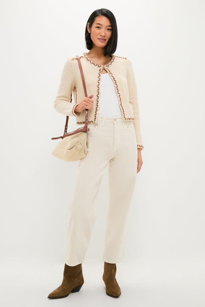 Young woman showcases classic Dark Olive Duerto Boot with pointed toe and Western-inspired seams, styled effortlessly with jeans and a knit bag for a fun, high-end look.