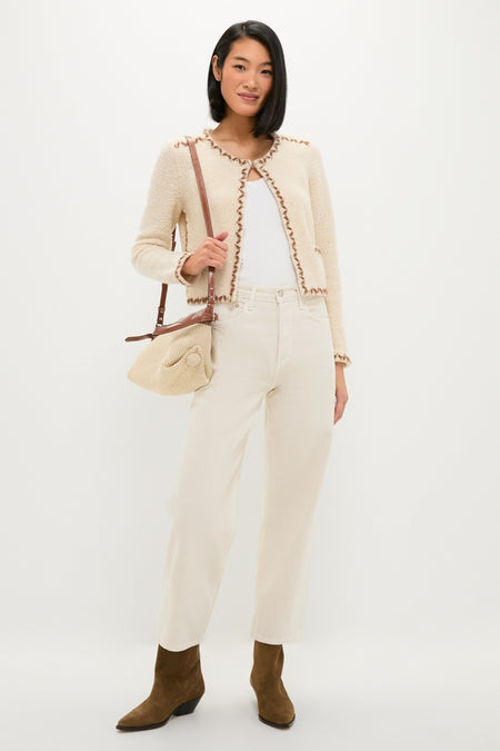 Young woman showcases classic Dark Olive Duerto Boot with pointed toe and Western-inspired seams, styled effortlessly with jeans and a knit bag for a fun, high-end look.