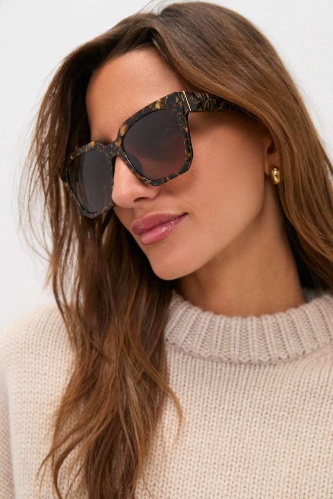Woman wearing Glitter Tortoise Ariana Polarized Sunglasses with oversized tortoiseshell frames, exuding a classic and effortless high-end style, paired with a fun, chic outfit.