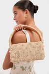 Young woman in a light sundress carries a classic woven straw bag, pairing effortlessly with a high-end Pearl Necklace with Carpe Diem Charm, embodying fun and stylish elegance.